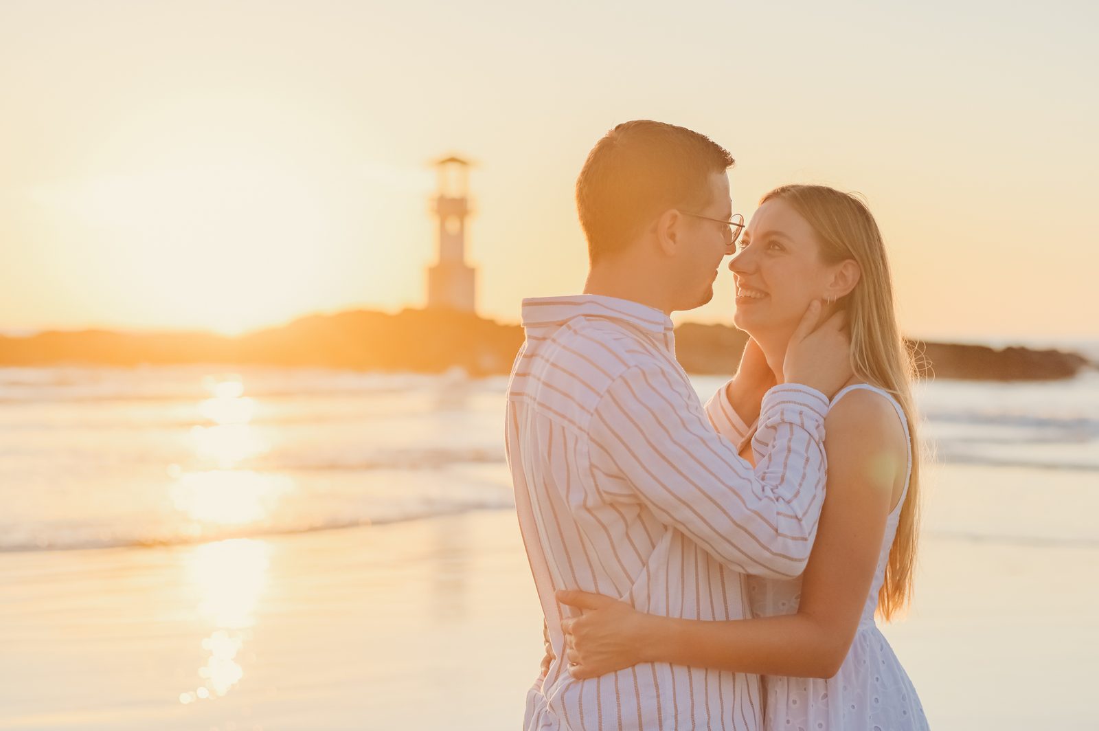 Couple embracing near a lighthouse at sunset in Khao Lak