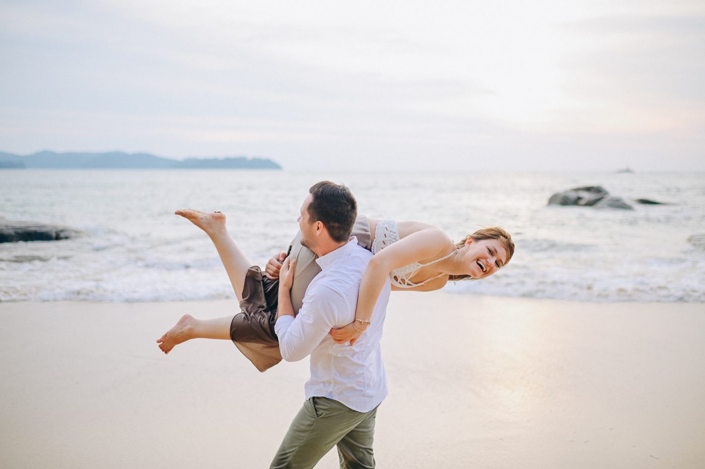 Couple playing piggyback on the beach in Khao Lak