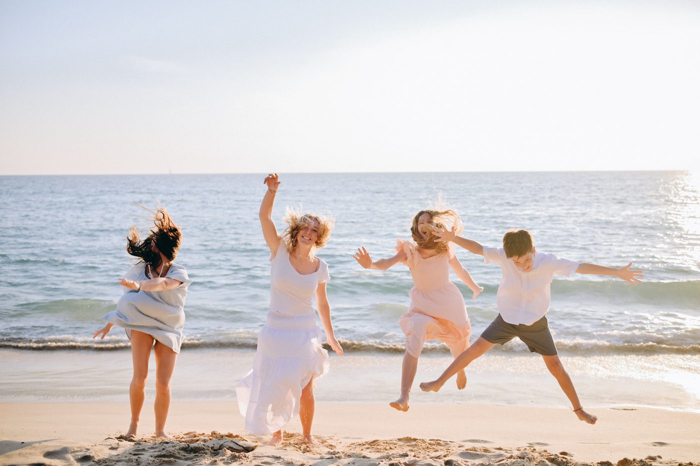 Family jumping for joy on the beach at sunset in Khao Lak