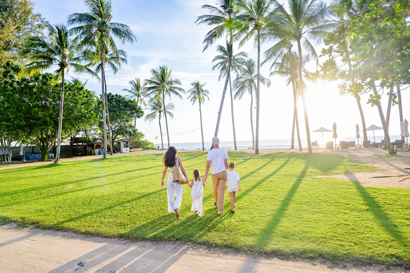 Family walking at sunset among palm trees in Khao Lak