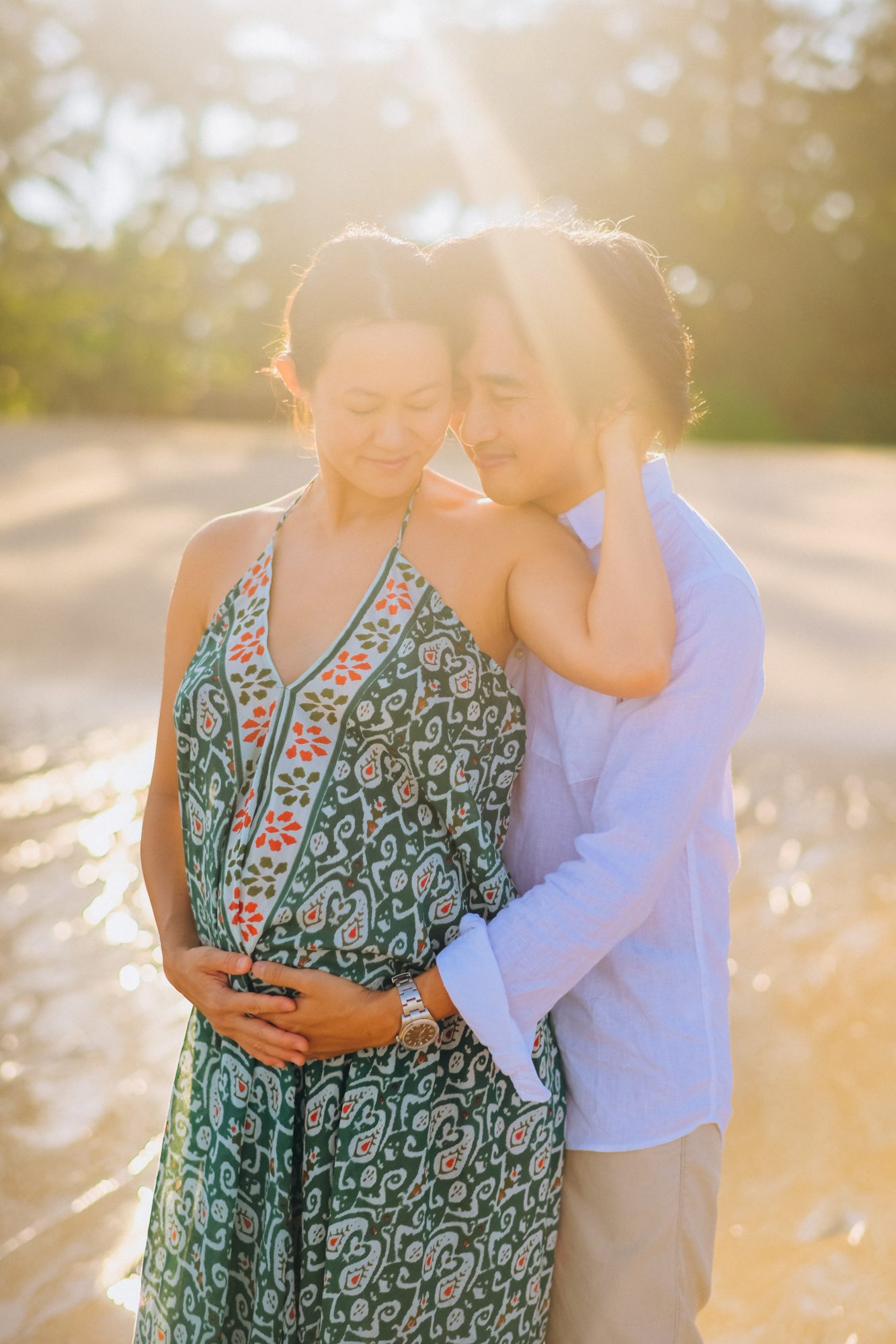Maternity couple embracing at golden hour in Khao Lak